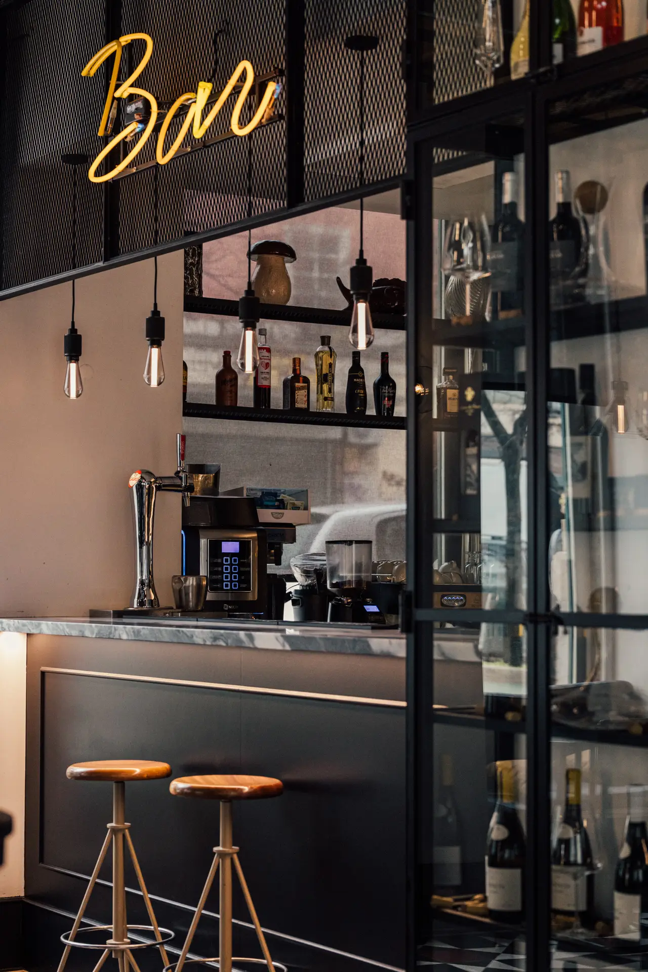 O balcão do bar com o letreiro «Bar» em néon e as garrafas na estante