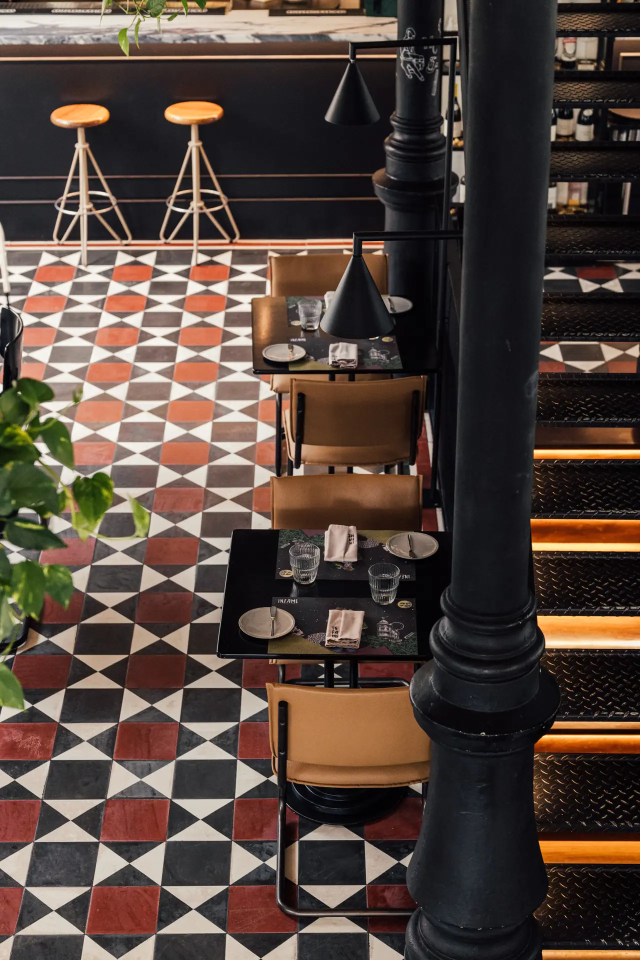 A sala vista de cima, com chão de mosaico vermelho, branco e preto e bancos altos ao balcão
