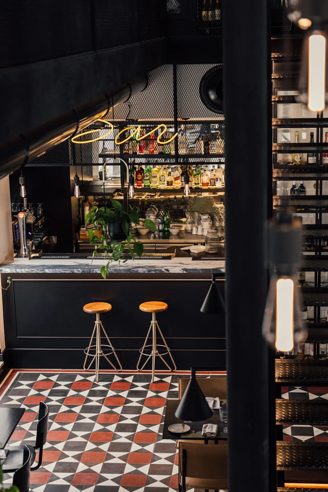O bar visto da sala, com o letreiro de néon e as colunas de ferro