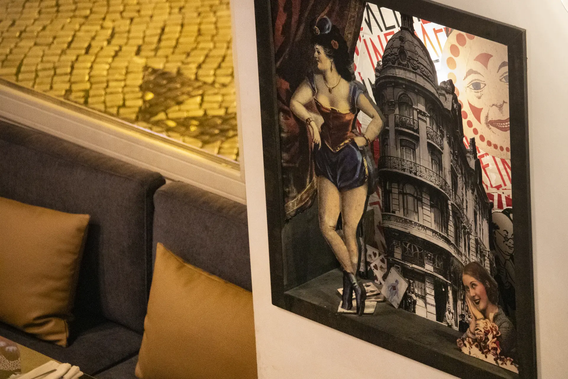 Sofá com almofadas douradas e uma colagem do prédio do hotel na parede